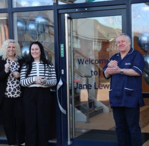 Male Jane Lewis Nurse and two female staff members, applauding at the entrance to the new Jane Lewis North Wales office