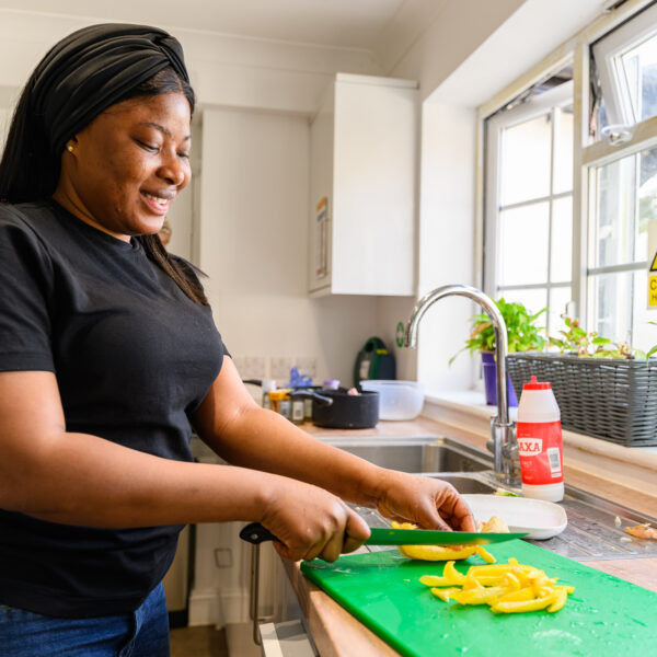 Female carer cutting up a yellow pepper in service kitchen for a service user's lunch