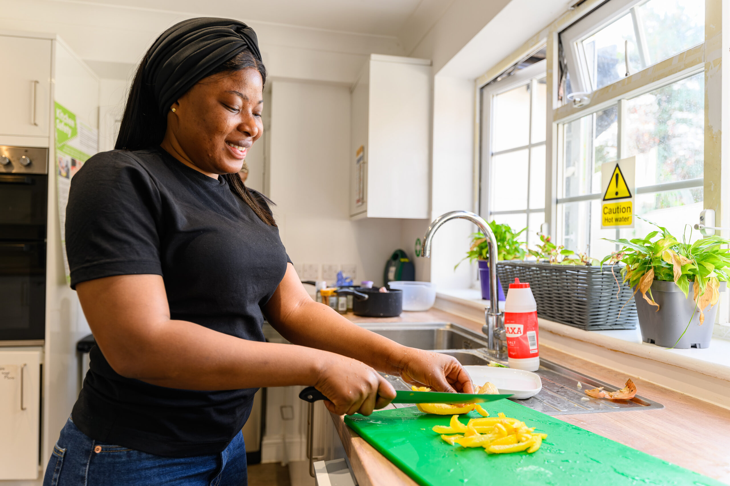 Female carer cutting up a yellow pepper in service kitchen for a service user's lunch