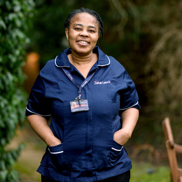 Jane Lewis nurse standing in a service garden surrounded by greenery