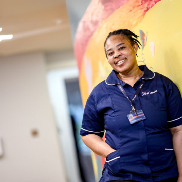 Jane Lewis female nurse standing in a service hallway in front of a bright mural