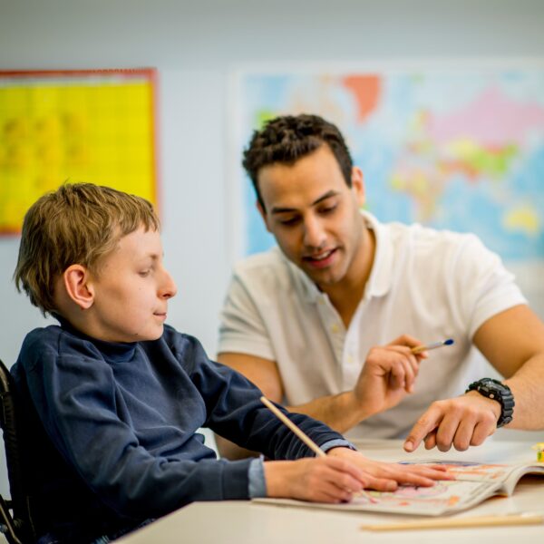 A Jane Lewis Support Worker helping a disabled child to paint in a SEND classroom