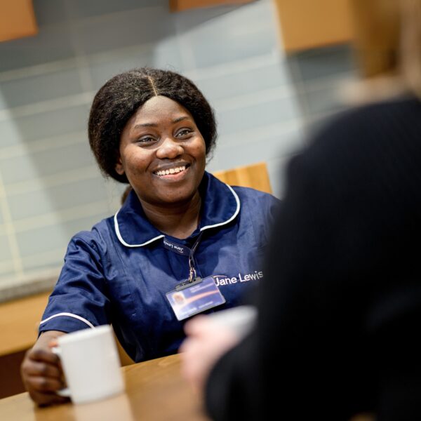 Female Jane Lewis nurse sat at table having a cup of tea with a service user