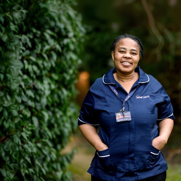 Jane Lewis nurse standing in a service garden surrounded by greenery