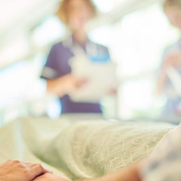Patient lying in hospital bed with Jane Lewis staff blurred out