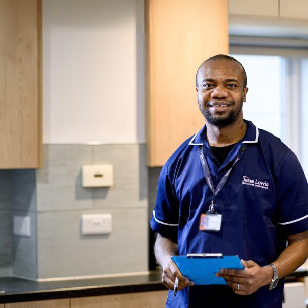 Male Nurse in Jane Lewis uniform standing in service kitchen with a blue clipboard
