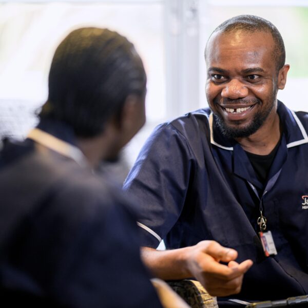 Two Jane Lewis male nurses sat indoors having a discussion
