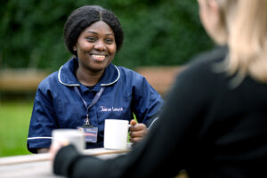 Jane Lewis Nurse sitting outside with service user drinking tea